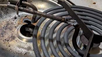 A corroded electric stove coil on a stained metal surface.