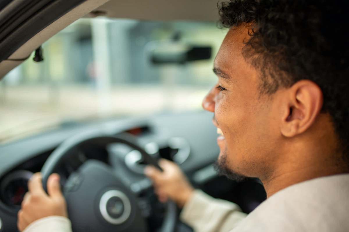 A man driving a car with his hands on the steering wheel.