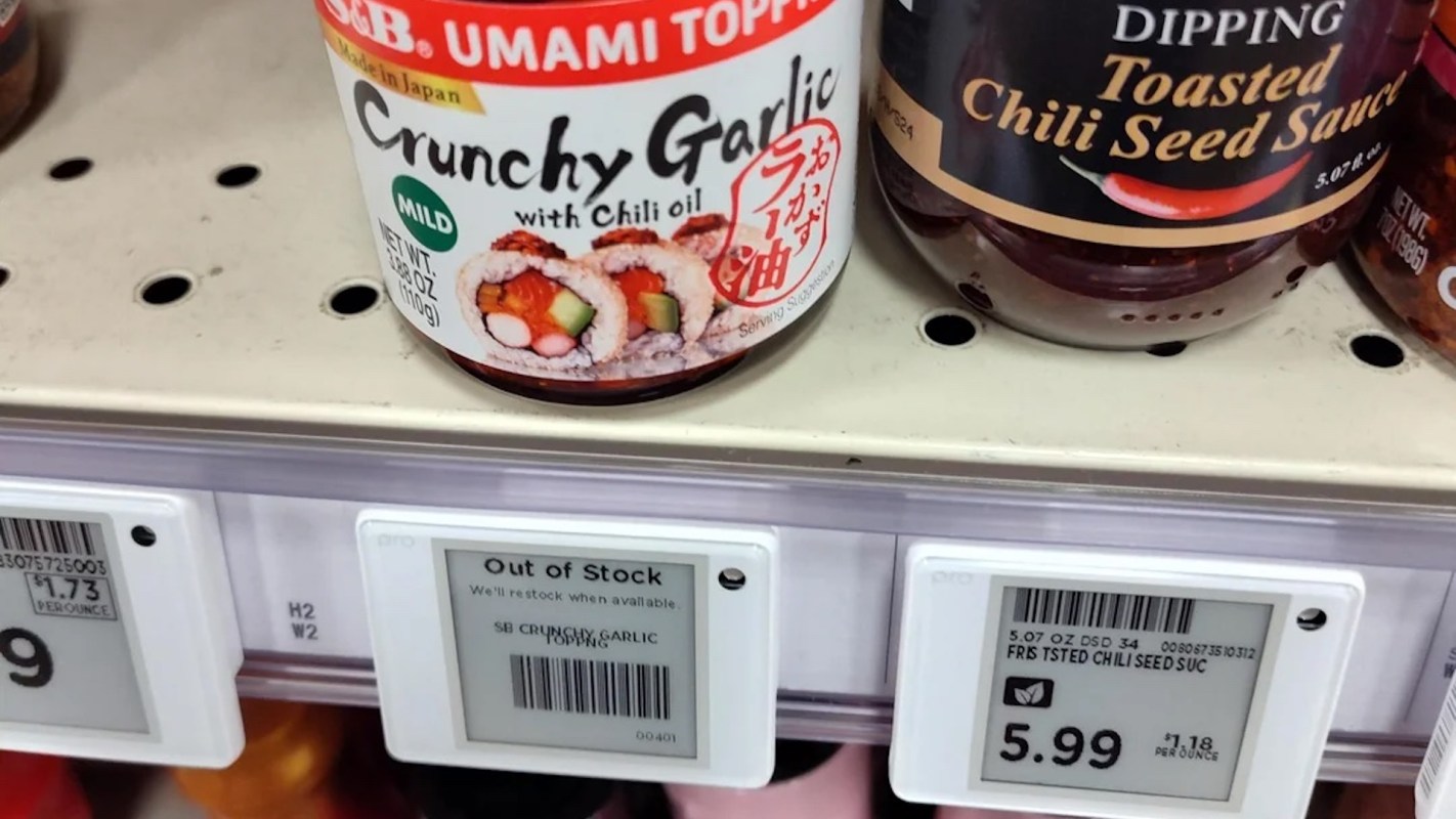 A shelf displaying jars of Crunchy Garlic topping and Toasted Chili Seed Sauce with a label indicating one is out of stock.