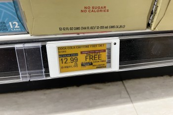An electronic shelf label displays the price of a pack of sodas in a grocery store