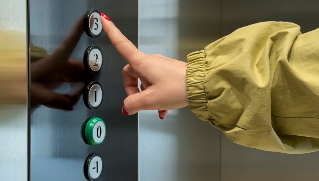 A person pushing an elevator button.