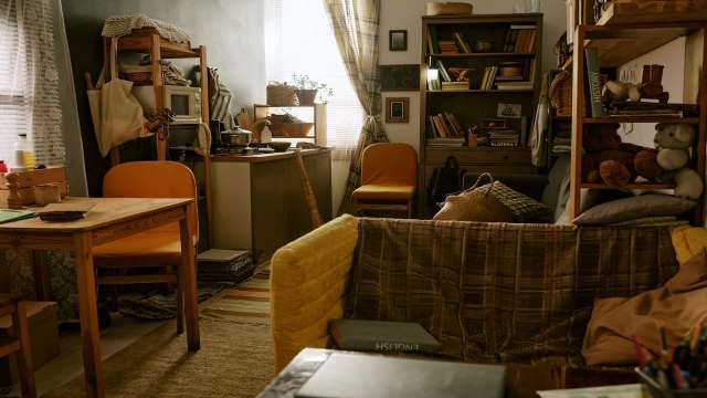 A cozy interior with a wooden table, chairs, bookshelves, and various household items arranged around the space.