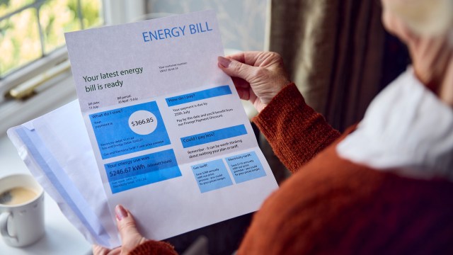 A person holds an energy bill detailing payment information and usage statistics.