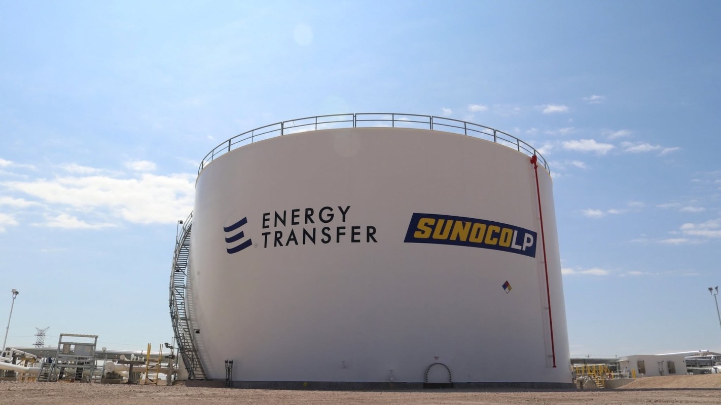 A large storage tank with logos for Energy Transfer and Sunoco LP under a clear blue sky.