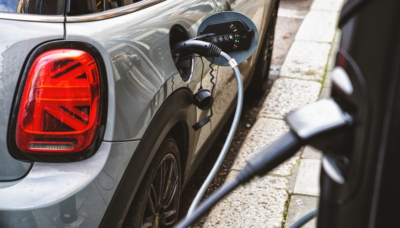 An electric car is plugged into a charging station on a city street.
