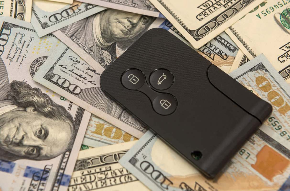A car remote on a pile of hundred-dollar bills.