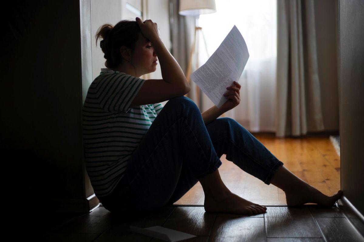 A woman sitting on the floor holding an eviction notice.