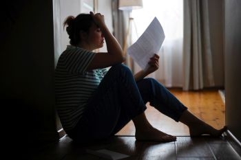 A woman sitting on the floor holding an eviction notice.