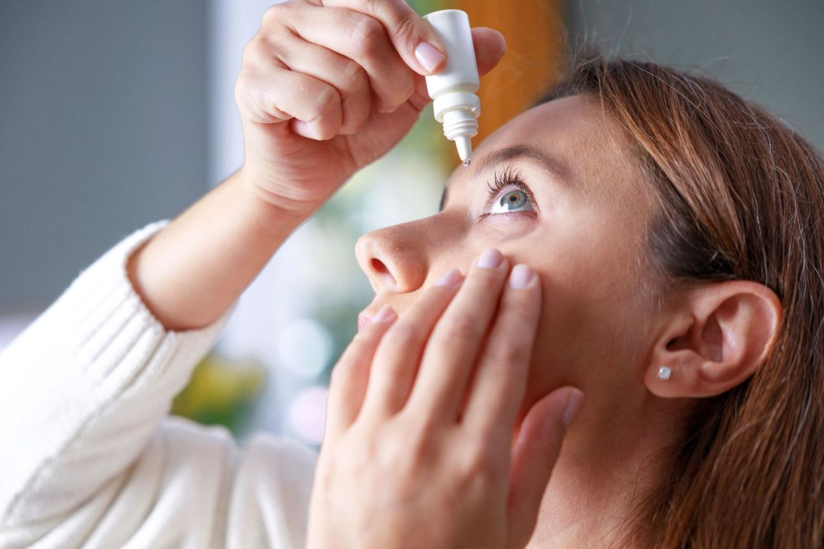 A woman using eye drops.