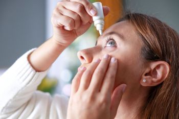 A woman using eye drops.
