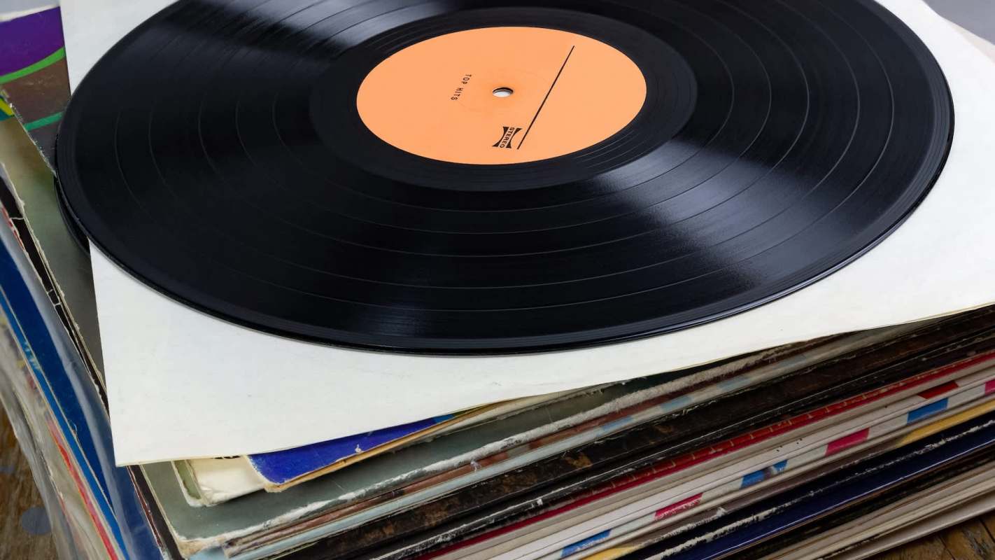 A vinyl record on top of a stack of album covers.