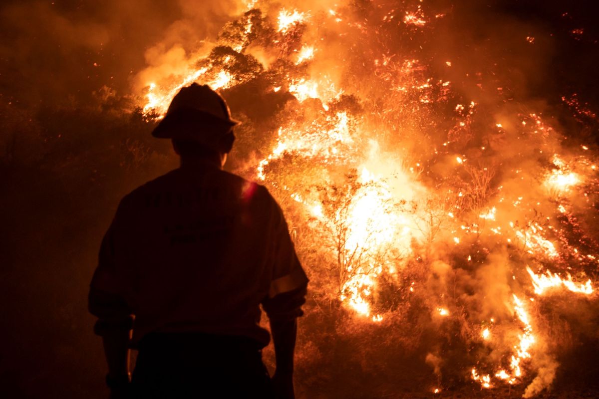 silhouette of a fire fighter with flames in front of him