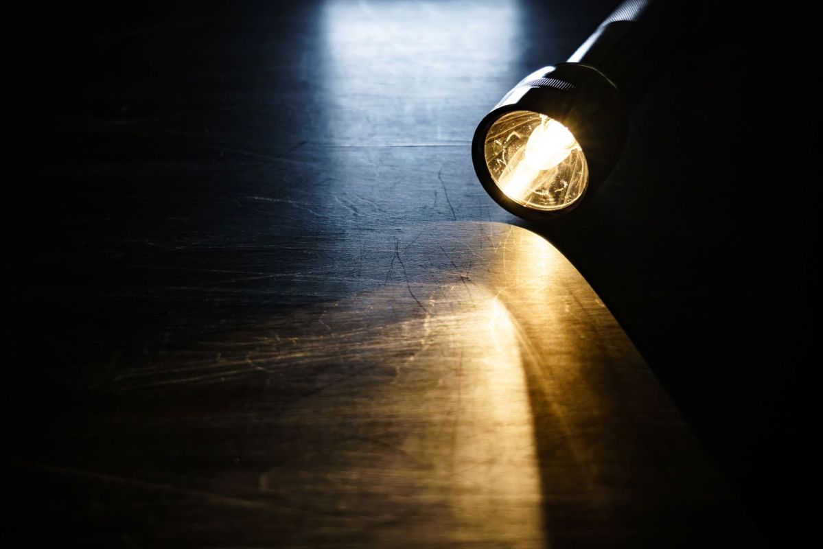 A lit flashlight on a wooden table.