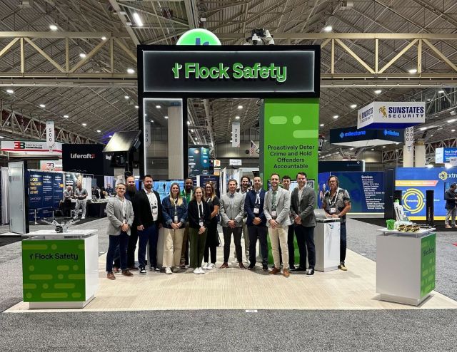 People standing under a Flock Safety sign.