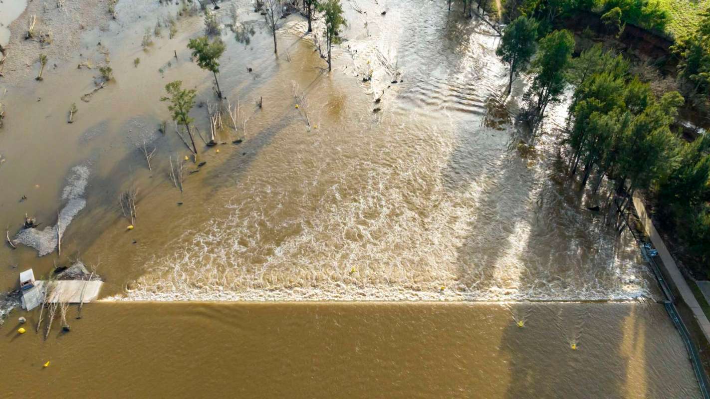 Aerial view of a flooded landscape with trees and a partially submerged road.