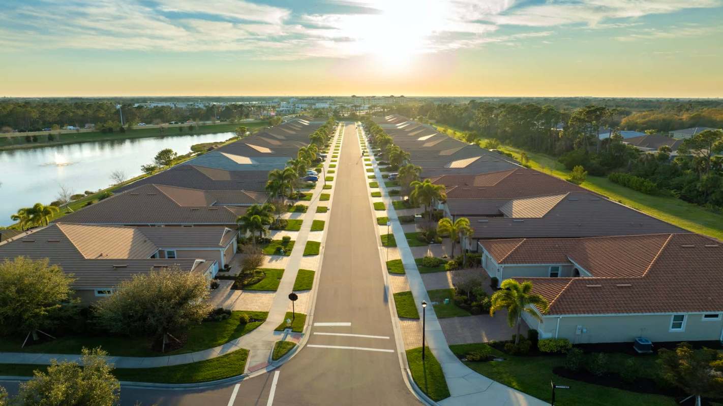 Aerial view of a residential neighborhood with houses lining a street and a lake nearby.