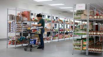 A person shops in a grocery store with shelves stocked with various food items.
