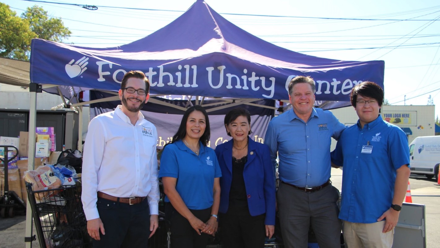 Five people stand in front of a tent labeled "Foothill Unity Center" with a food cart nearby.