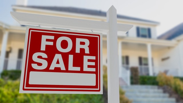 A "For Sale" sign is displayed in front of a residential home.