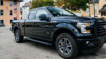 A black Ford F-150 truck parked in an urban area with buildings in the background.