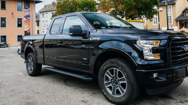 A black Ford F-150 truck parked in an urban area with buildings in the background.