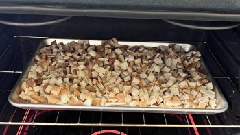 Cubed bread on a baking tray inside an oven.
