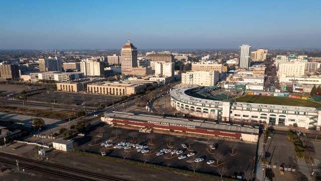 Aerial view of downtown Fresno with buildings, parking lots, and a baseball stadium.