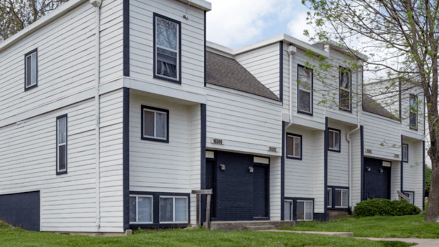 A row of modern white townhouses with black accents and grassy landscaping.