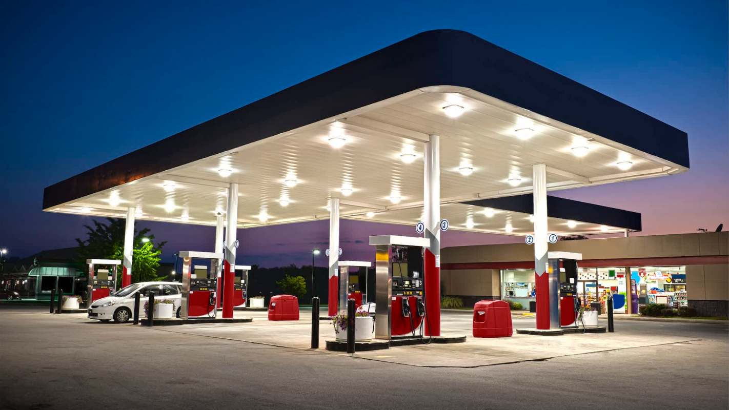 A gas station with multiple fuel pumps illuminated at night.