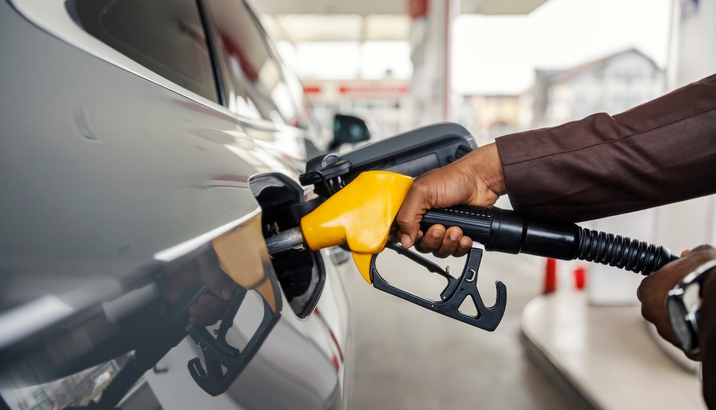 A person fills a vehicle with fuel at a gas station using a fuel pump.