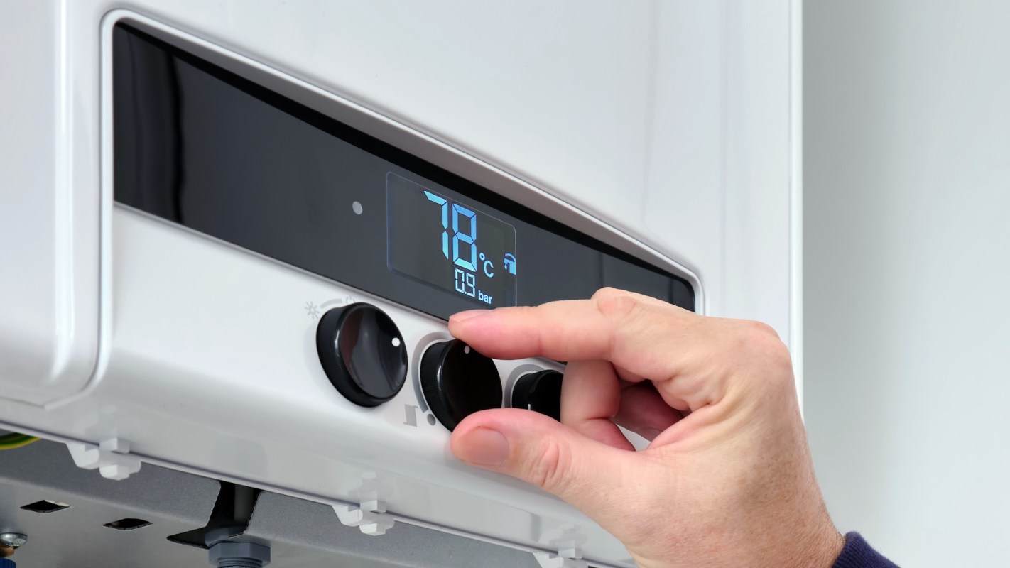 A hand adjusting the temperature on a digital thermostat display.