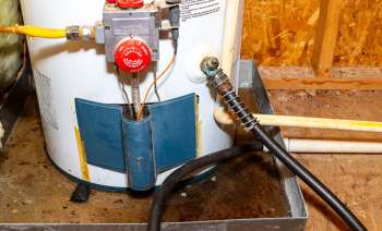 A water heater with various pipes and valves in a basement setting.