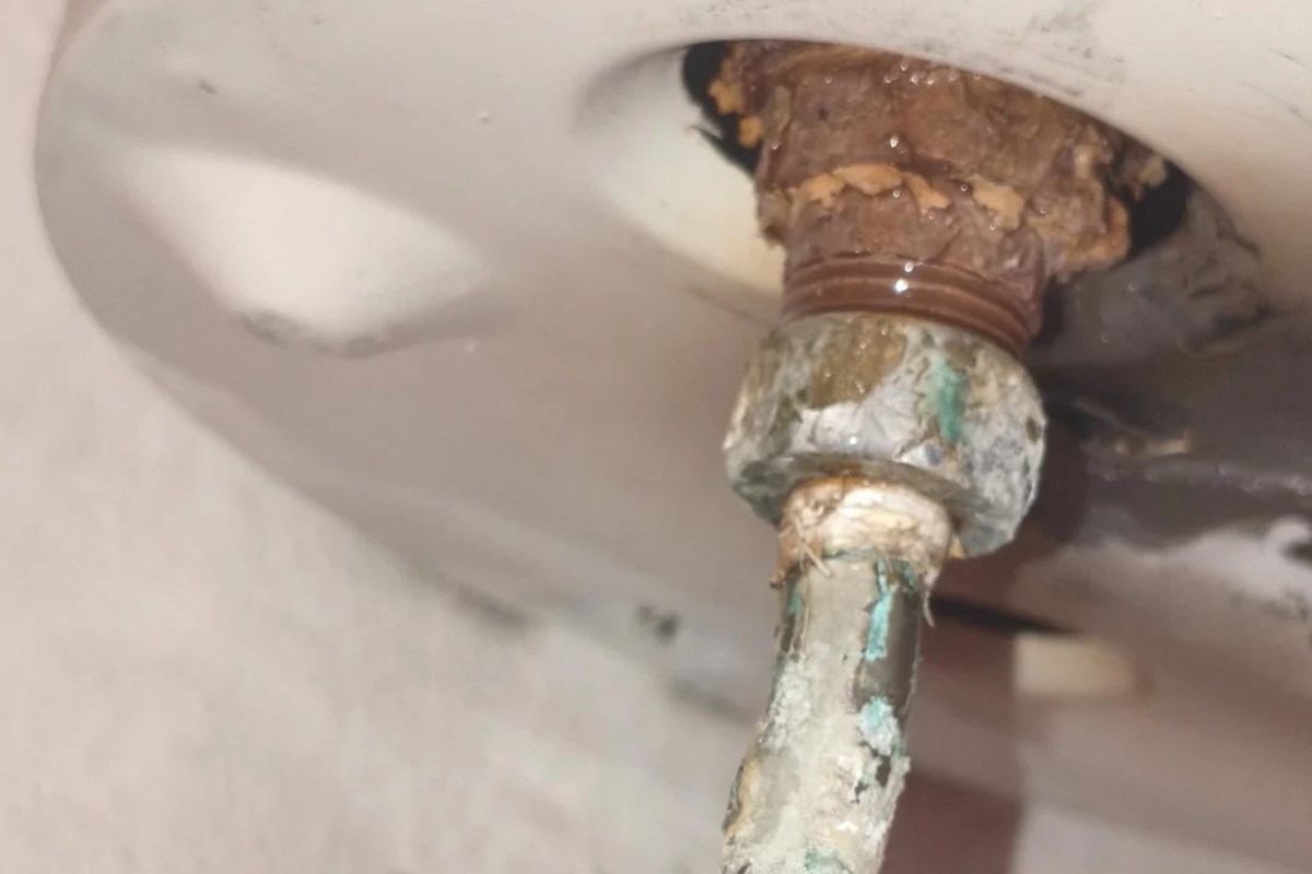 A corroded pipe fitting with visible rust and moisture.