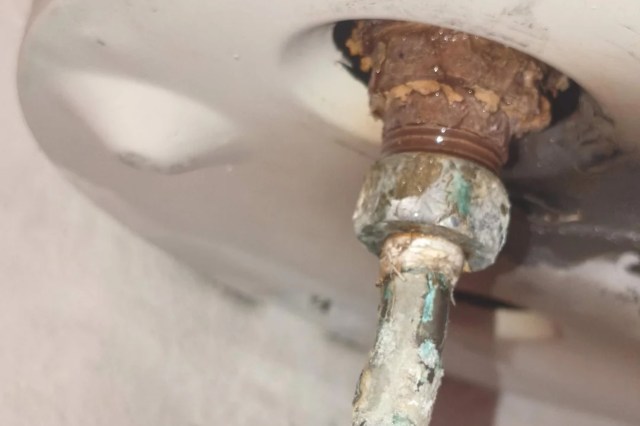 A corroded pipe fitting with visible rust and moisture.