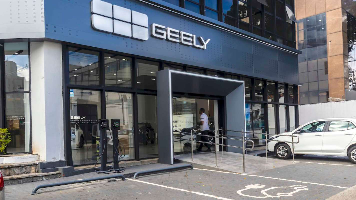 A Geely car dealership with charging stations and someone entering the building.