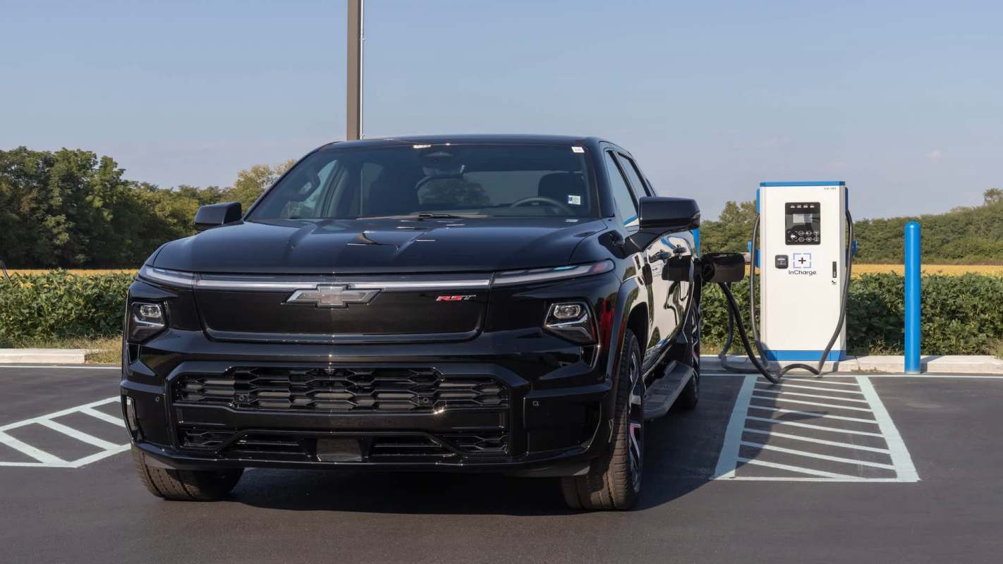 A black Chevrolet electric truck is parked at a charging station.
