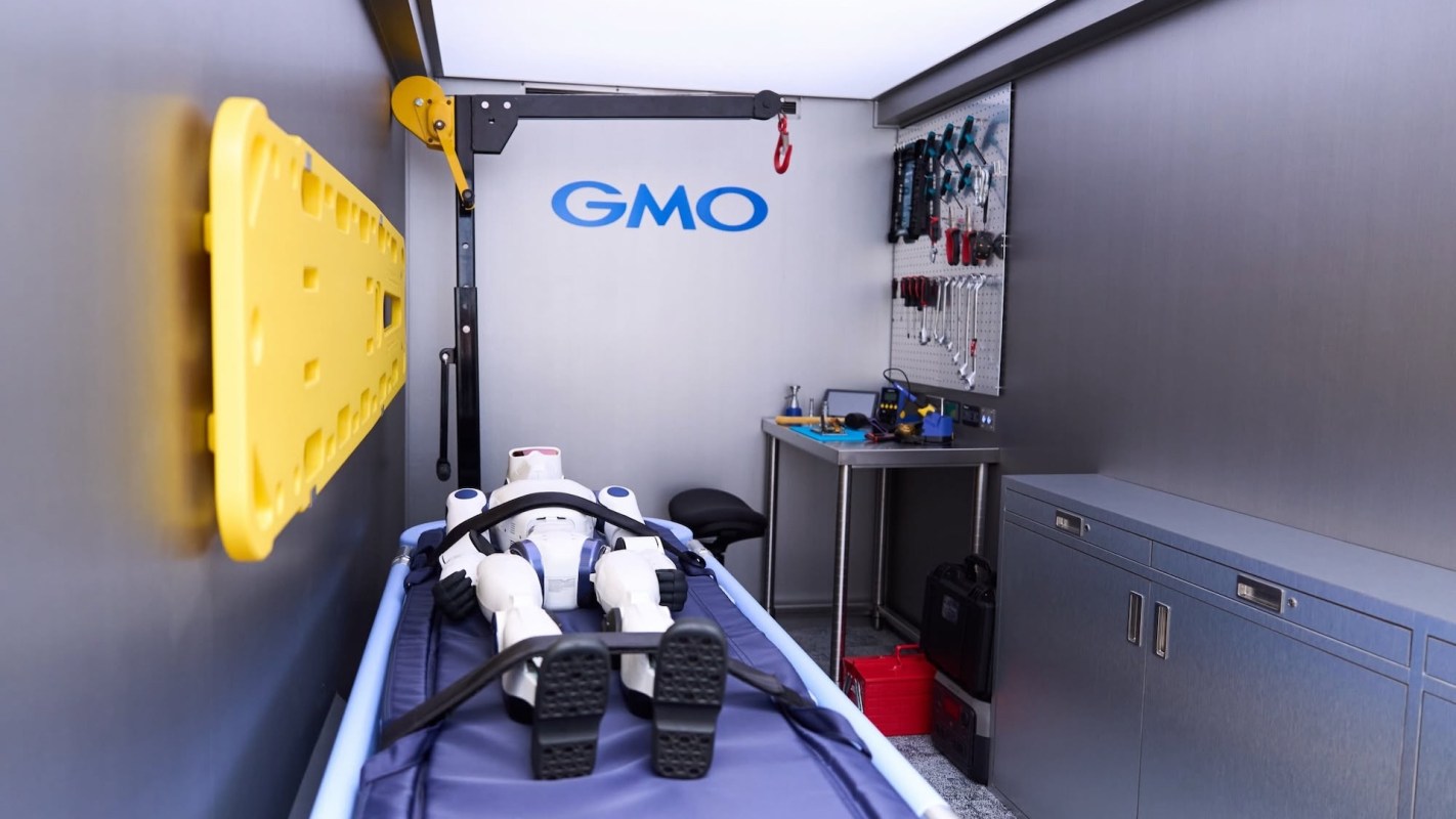 A robotic mannequin on a stretcher inside a room with tools and equipment.