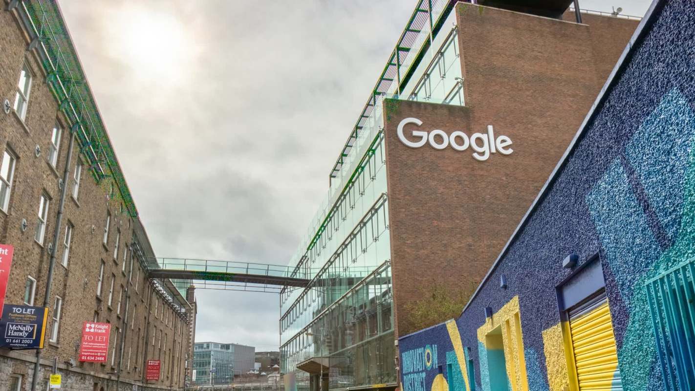 A Google office building in Dublin, Ireland, with a glass facade and colorful mural on the adjacent wall.