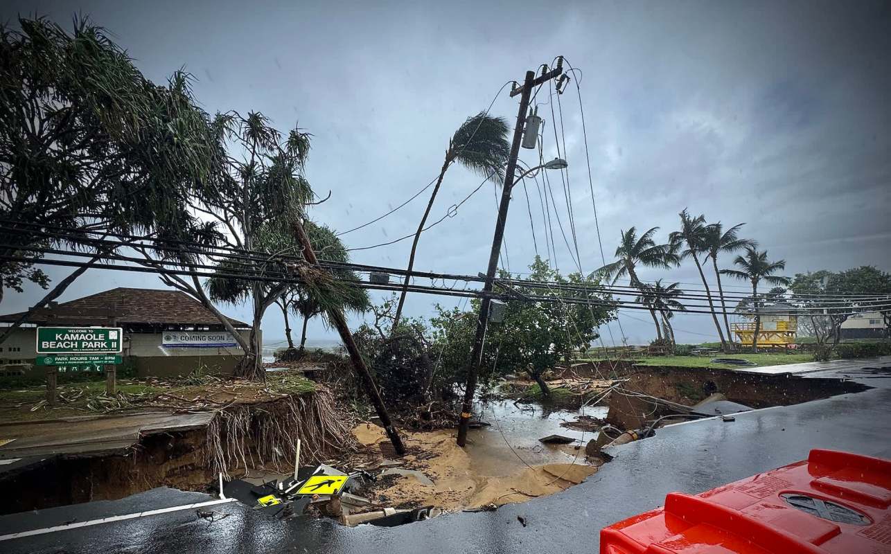 A collapsed road with downed power lines and damaged trees near Kamole Beach Park in Hawai'i.