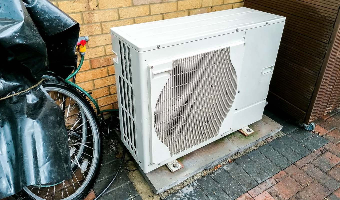 An air conditioning unit by a brick wall.