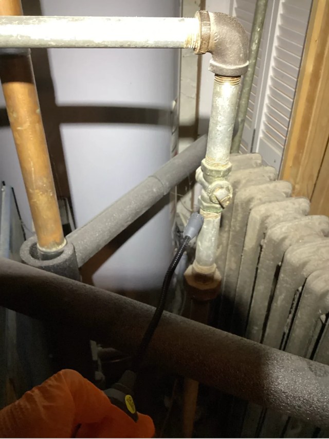 A person examining boiler pipes.