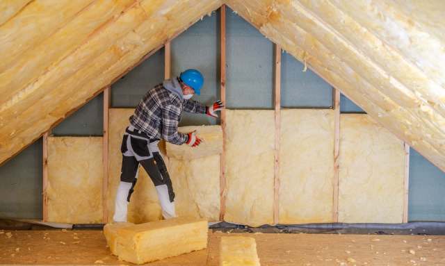 A person installing insulation in an attic.