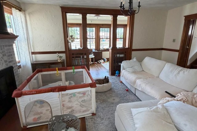 A living room with a playpen, a dog bed, and scattered toys on the floor.