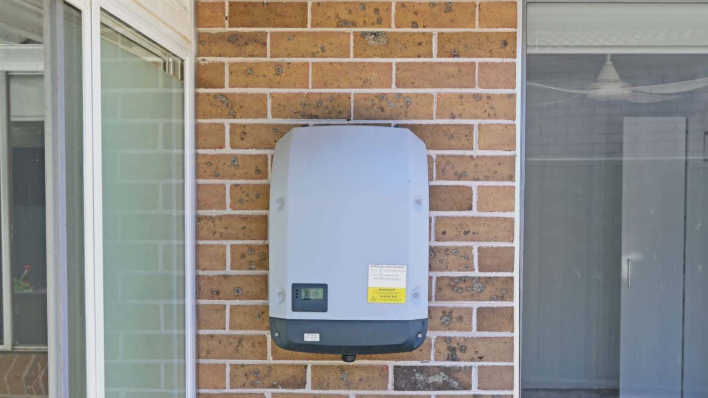 A home battery mounted on a brick wall next to a window.