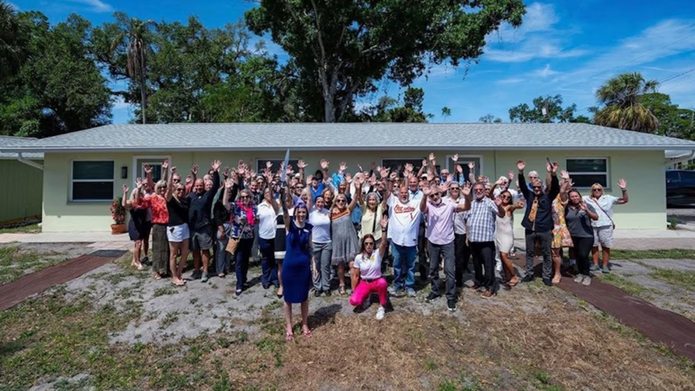 Supporters of Second Heart Homes cheering outside a single-story house.