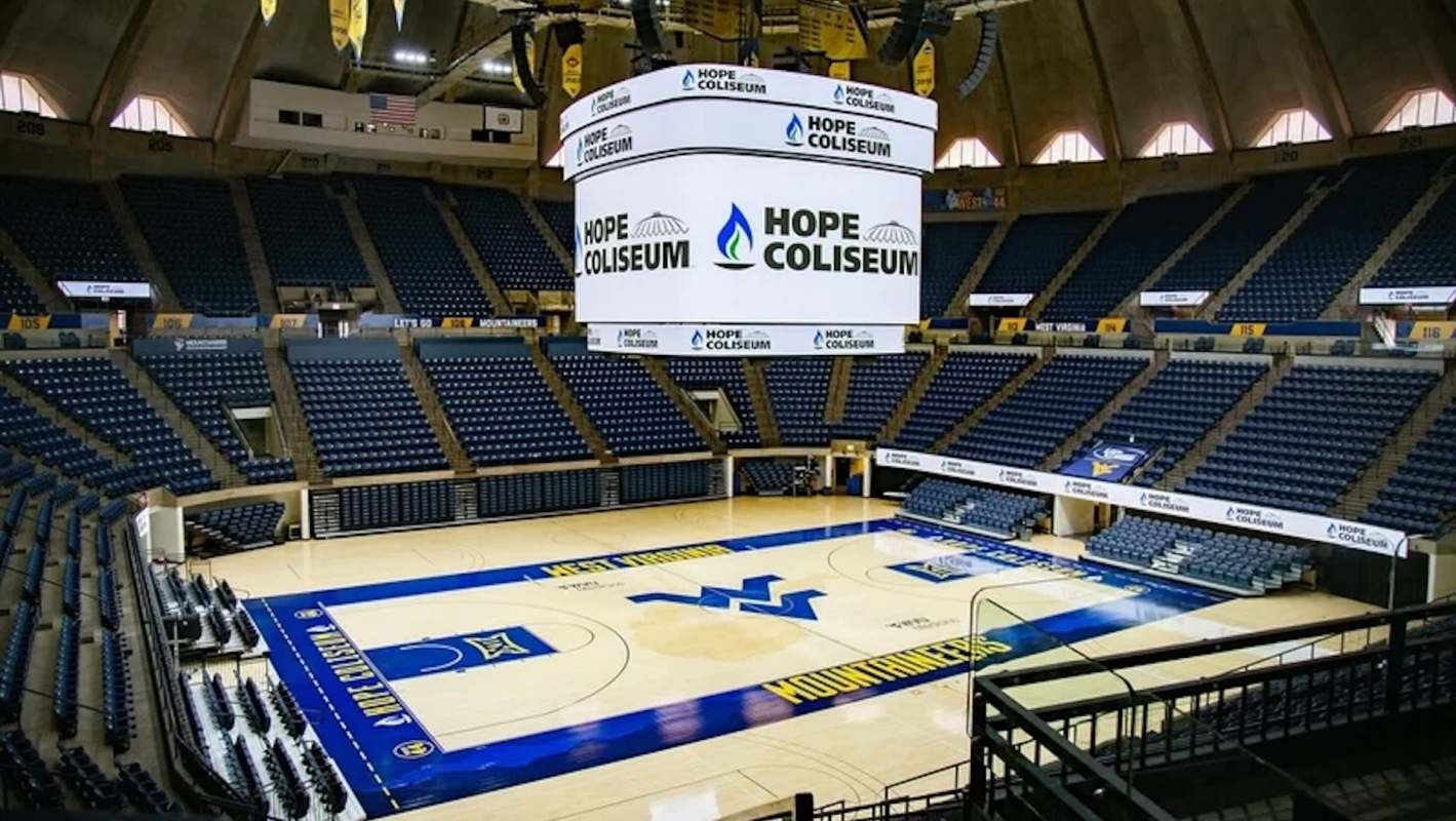 An indoor sports arena featuring empty seating and a large scoreboard displaying "Hope Coliseum."
