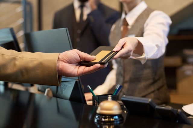 A person hands a wallet to a person at a hotel desk.