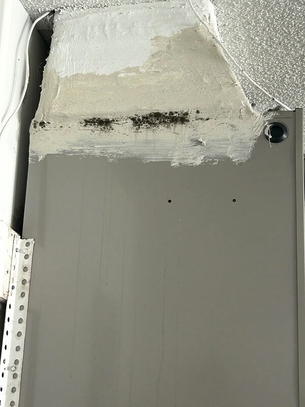A gray heating unit mounted on a wall with visible specifications and a warning label.