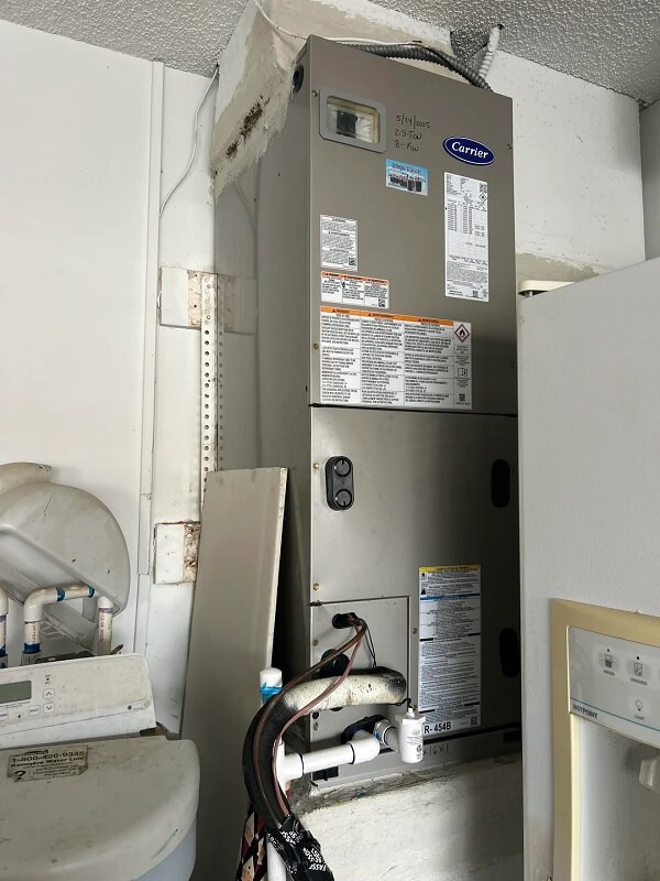 A gray heating unit mounted on a wall with visible specifications and a warning label.