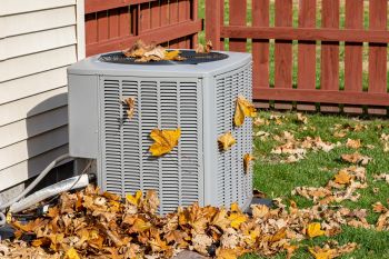 HVAC condenser outdoors with leaves